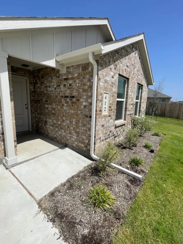 White gutters and downspout on a Dallas–Fort Worth brick home