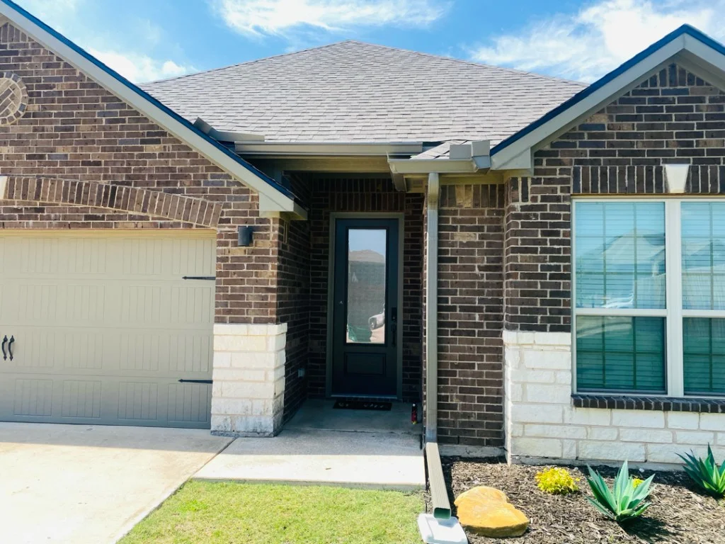 Bronze aluminum gutters and downspout on a Dallas–Fort Worth brick home