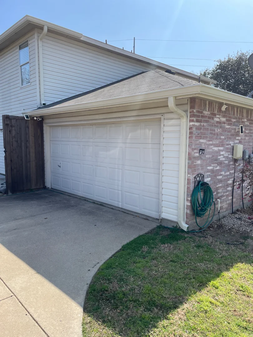 White gutters on a brick garage along a Carrollton driveway