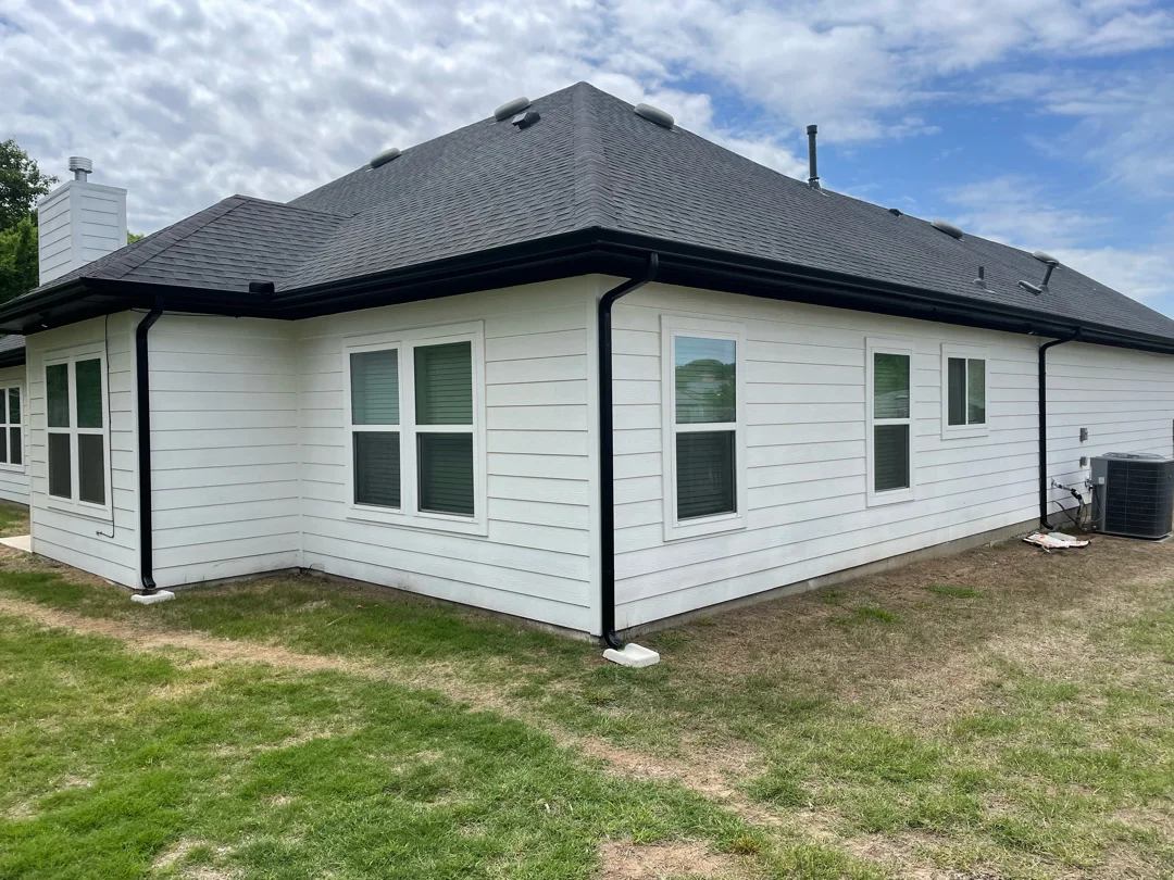 Black gutters on the rear elevation of a white-siding home