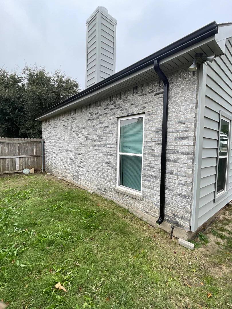 Black seamless gutters on a light-brick modern Dallas home