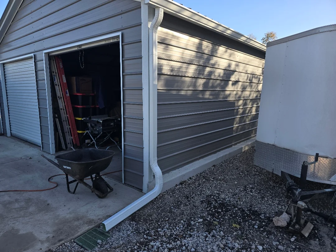 White downspout and gutters on a gray metal workshop