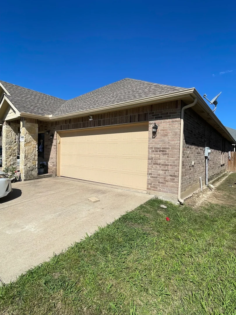 Tan gutters on a Frisco brick home with a two-car garage