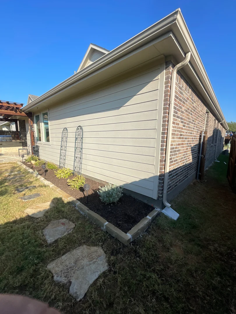 Tan gutters on a Grapevine brick home with landscaping