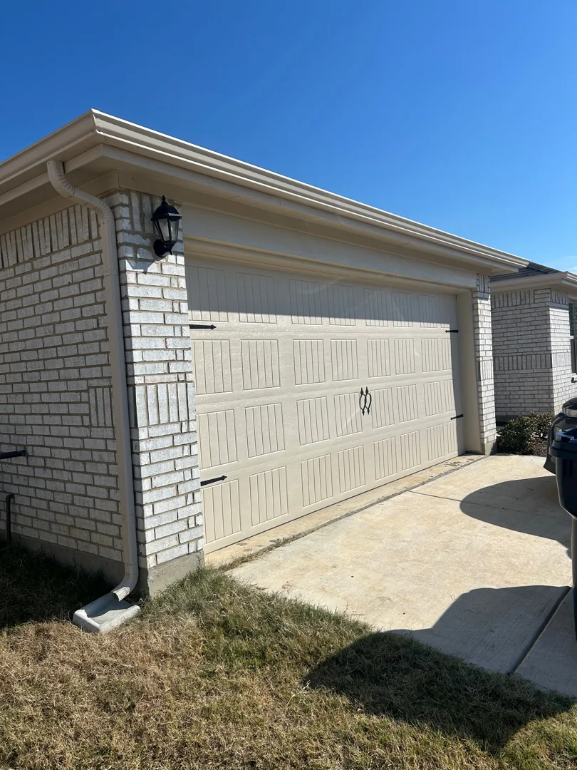Almond gutters on a beige garage and brick home in Irving