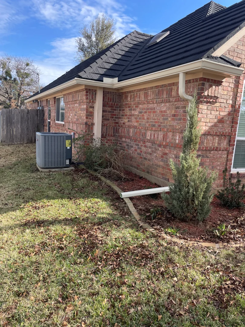 Gutter extension directing runoff into a mulch bed in Keller
