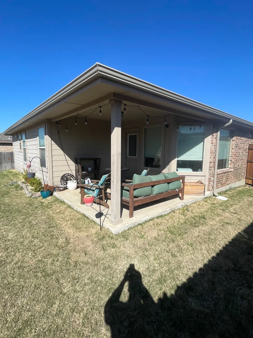 Beige gutters on a covered patio with string lights in Keller