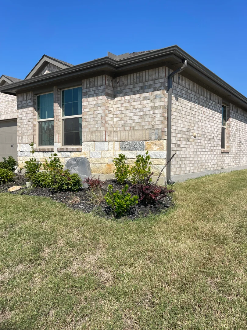 Bronze gutters on a Prosper home with stone wainscot